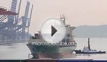 Large container ship pushed by tugboat